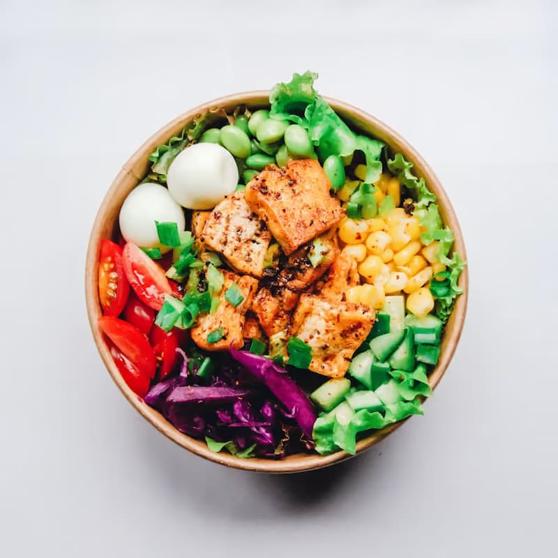 Bowl de ensalada con pollo, maíz, tomate y verduras frescas